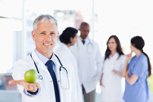 Smiling doctor holding a green apple in his right hand