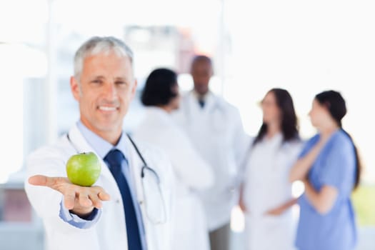 Smiling mature doctor holding an apple