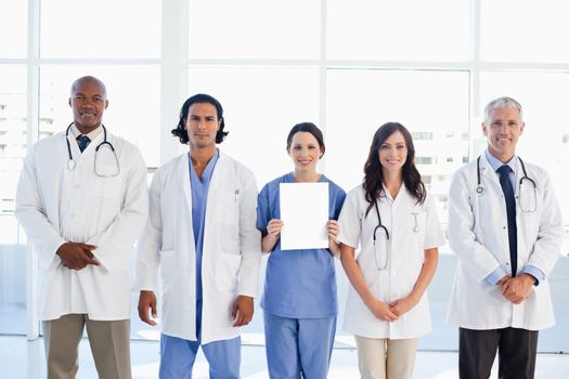 Medical people surrounding a new intern which is holding a blank sheet