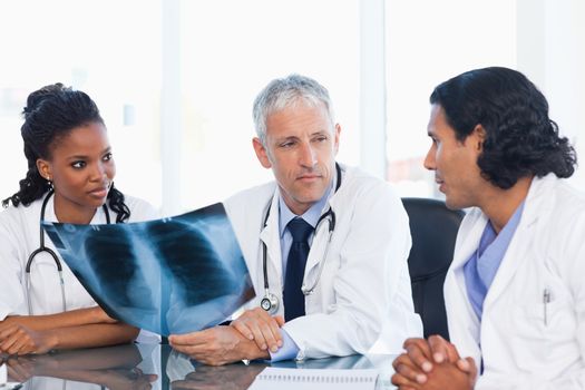 Serious doctor looking at an x-ray with two nurses