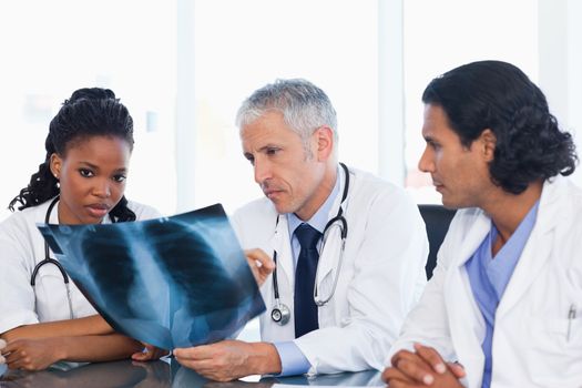 Calm doctor with two co-workers seriously working on an x-ray of lungs