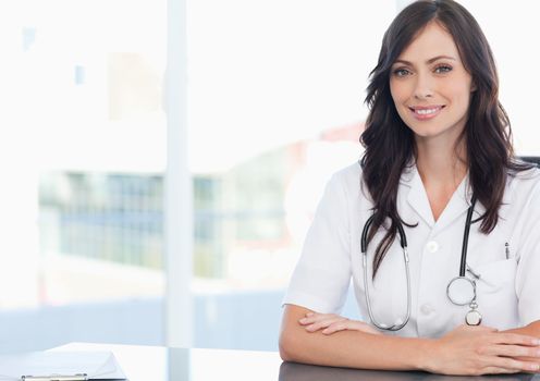 Young doctor sitting at the desk next to a clipboard