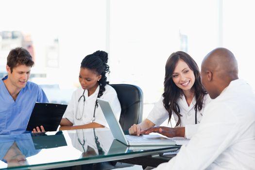 Smiling medical team working both on a laptop and a clipboard