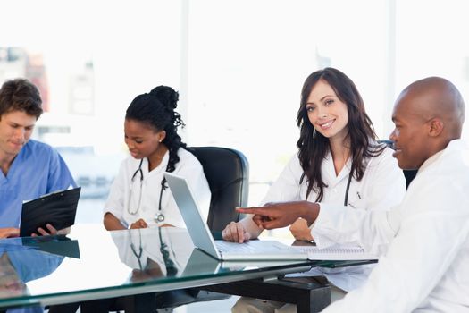 Smiling medical interns working on the computer near co-workers