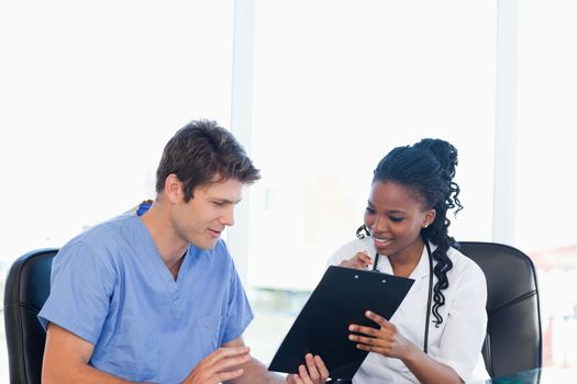 Two smiling nurses working on a professional clipboard in a well-lit room