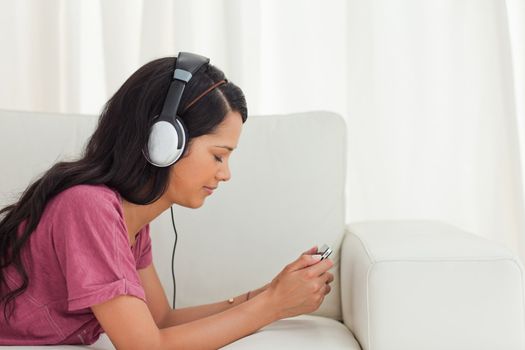 Young Latino listening music with her smartphone on a sofa