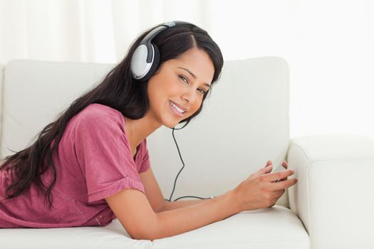 Young Latino smiling while listening to music on a sofa with a smartphone