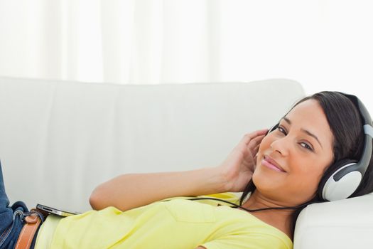 Portrait of a young Latino listening music on a smartphone while lying on a sofa