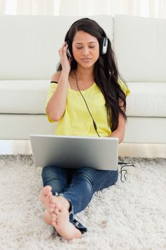 Beautiful Latin watching video on a laptop while sitting on the floor