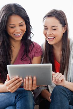 A close up half length shot of a pair of laughing women looking at the tablet pc together