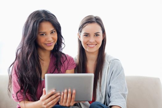 A pair of women looking at the camera as one woman holds a tablet pc 