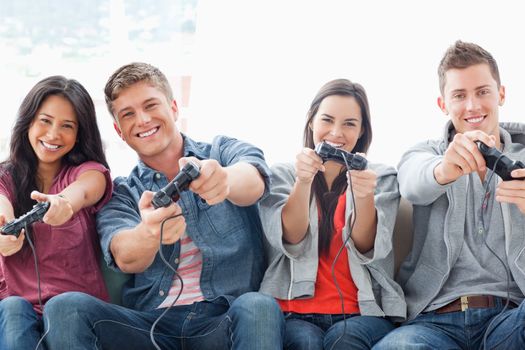 A happily smiling group of friends playing a game together while sitting on the couch