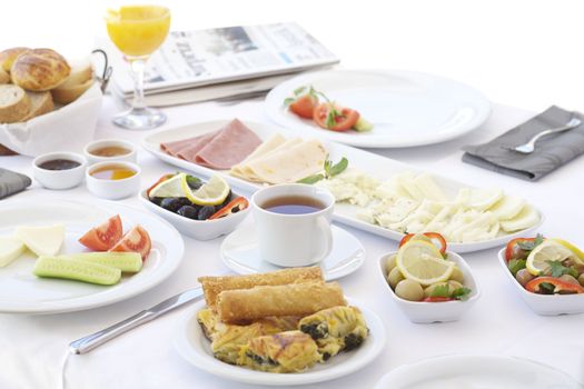 Breakfast table with cheese, tomatoes, olives, cucumber and pastries