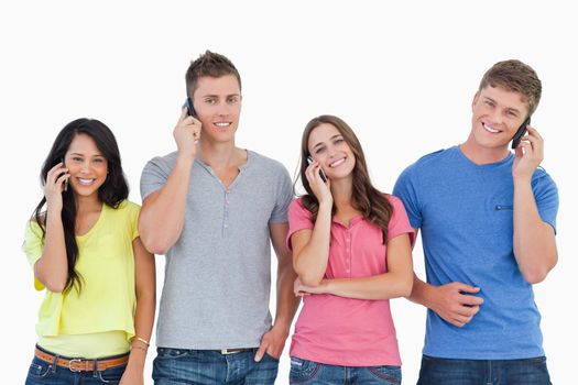 A group of friends of smiling as they all make calls and look into the camera 