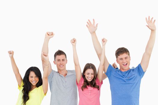 Four friends celebrating together with their hands in the air as they all look at the camera 