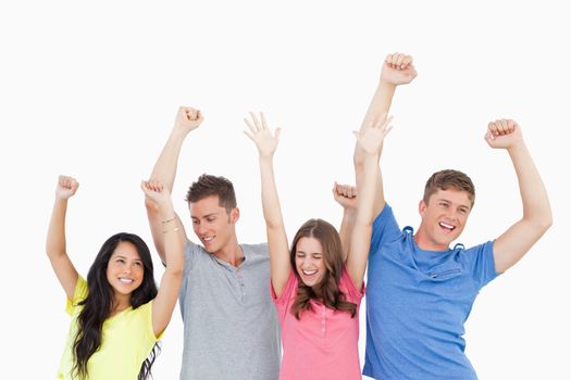 A group of friends party together with their hands in the air