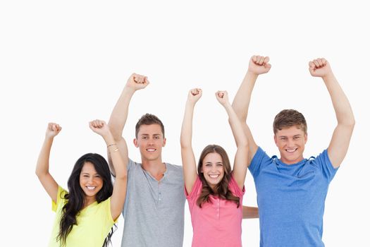 A smiling group as they celebrate with their hands raised in the air 