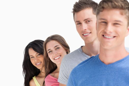 A smiling group of people standing at angle while they all smile and look at the camera 