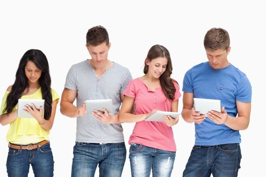 A smiling group of people using tablet pc's as they stand beside one another