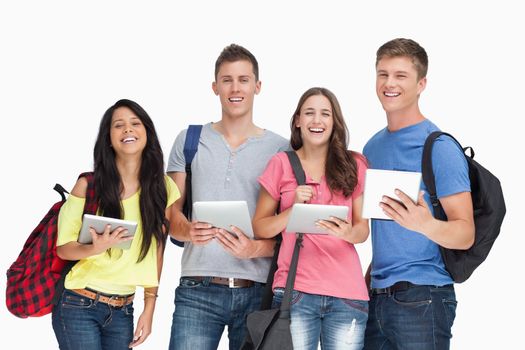 A smiling group of students with backpacks and tablets as they look into the camera 