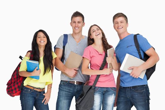 A laughing group of students with notepads and backpacks as they look at the camera