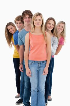 A full length shot of a smiling group standing behind one another at various angles while lookinng into the camera