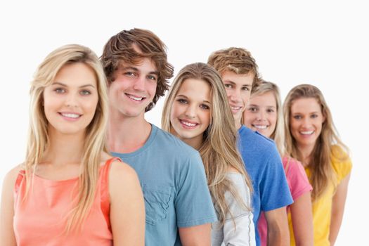 A smiling group standing behind each other at an angle while looking into the camera