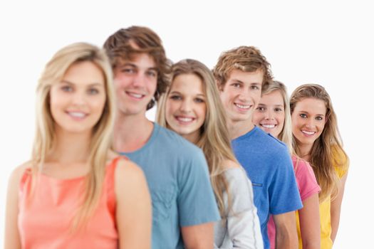 A smiling group standing behind each other at an angle while looking at the camera