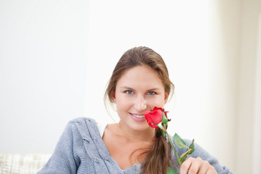 Woman holding a rose while smiling grey background