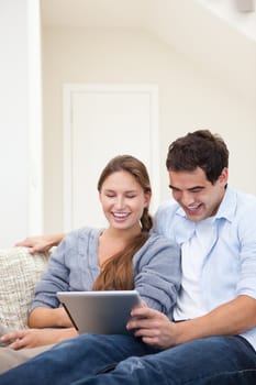 Couple laughing while holding a laptop in a sitting room