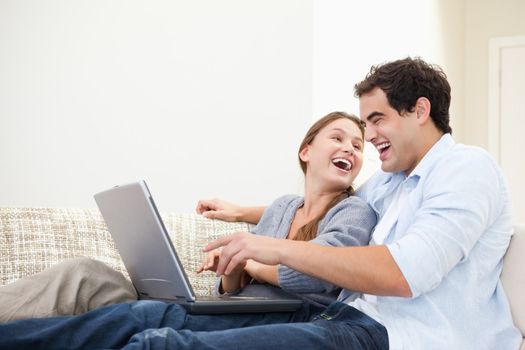 Couple laughing while typing on a computer indoors
