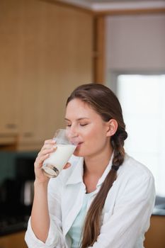 Women drinking a glass of milk in a kitchen