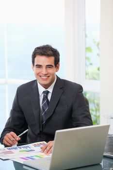 Man working on graph while smiling in an office