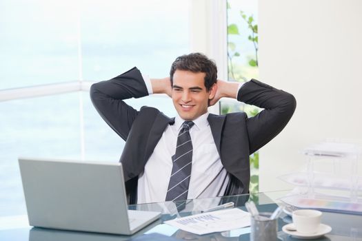 Man crossing his arms behind his head  in an office