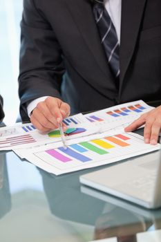 Men pointing a graph with a pen in an office