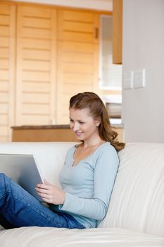 Woman sitting on a sofa while looking at laptop in a sitting room