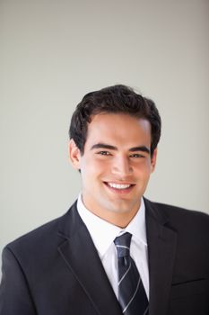 Businessman standing while smiling against grey background