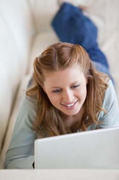 Woman lying on a sofa while using a computer indoor