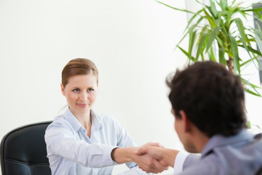 Businesspeople looking each other while shaking hands in an office