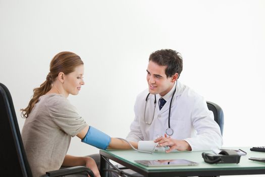 Doctor taking blood pressure of a patient against grey background