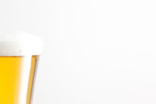 Glass full of foam and beer against a white background