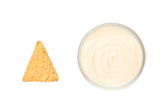 A bowl of white dip and a nacho placed side by side