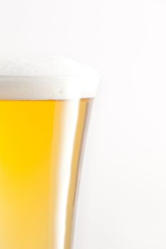 Glass full of beer and foam against a white background