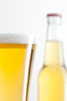 Glass and bottle full of beer against a white background