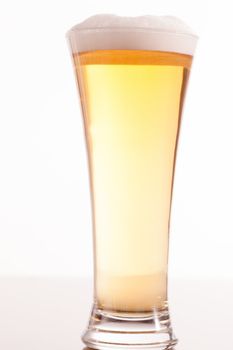 Full glass filled with beer and foam against a white background
