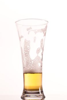 Almost empty glass of beer against a white background