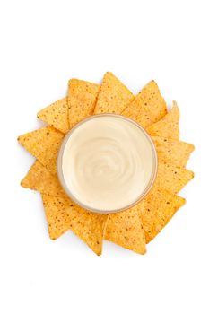 Nachos placed around a bowl of white dip against a white background