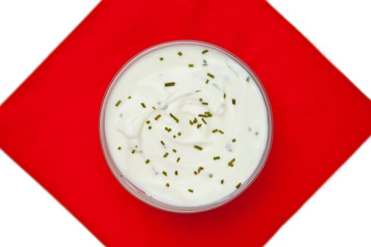 Bowl of dip with herbs on a red napkin against a white background