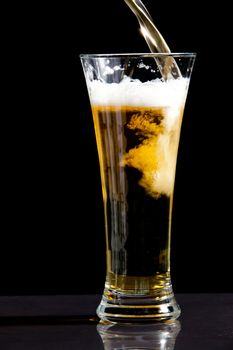 Glass being filled with beer against a black background