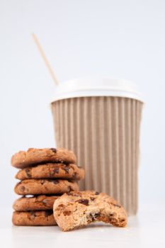 Five cookies and an half eaten cookie and a cup of coffee placed together against a white background